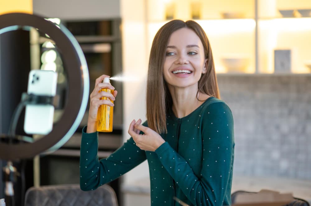 the girl is spraying hair serum in her hair